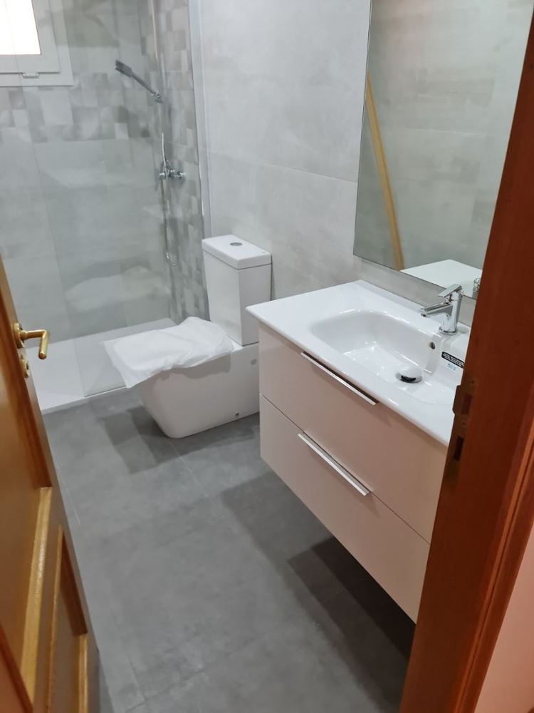 Baño reformado con ducha, mueble de lavabo con cajones y espejo
