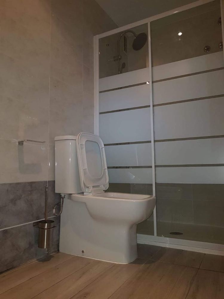 Baño con mampara de ducha de cristal con vinilo esmerilado e inodoro