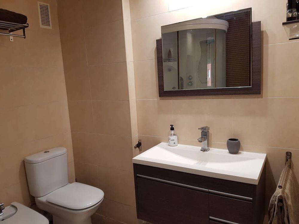 Baño con mueble de lavabo oscuro y espejo