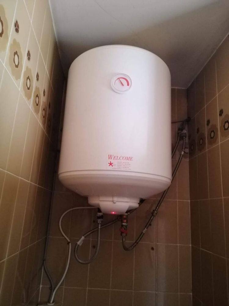 Termo eléctrico blanco instalado en la pared de un baño